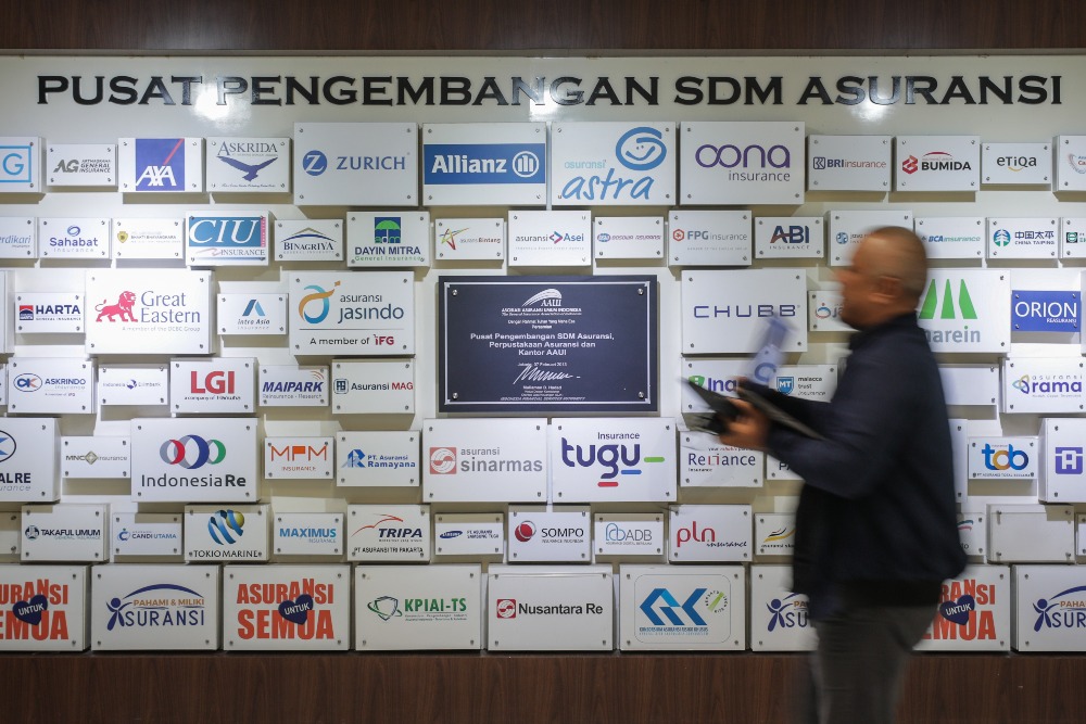 Karywan beraktivitas di dekat logo-logo asurani di kantor Asosiasi Asuransi Umum Indonesia (AAUI) di Jakarta, Rabu (3/7/2024)./Bisnis-Fanny Kusumawardhani