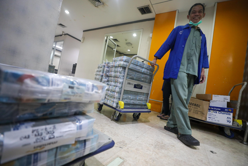 Pegawai merapikan uang rupiah di cash center Bank Mandiri di Jakarta.