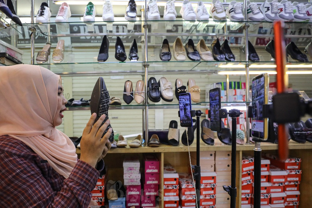 Pedagang memasarkan produk sepatu melalui siaran langsung platform penjualan daring di pasar Tanah Abang, Jakarta, Selasa (12/12/2023). Bisnis/Arief Hermawan P