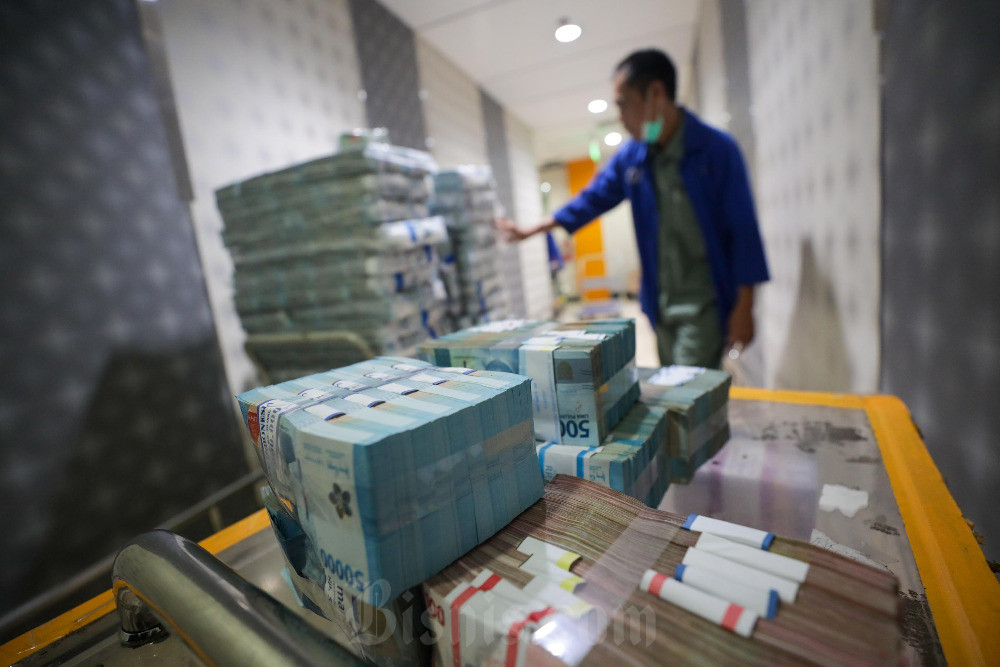 Pegawai merapikan uang rupiah di cash center Bank Mandiri di Jakarta.