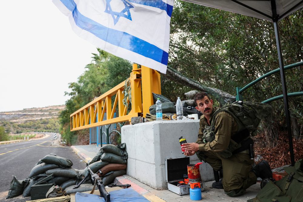 Seorang tentara Israel menyiapkan kopi saat dia menjaga pos pemeriksaan dekat perbatasan dengan Lebanon, di Israel utara, 1 November 2023. / REUTERS-Violeta Santos Moura
