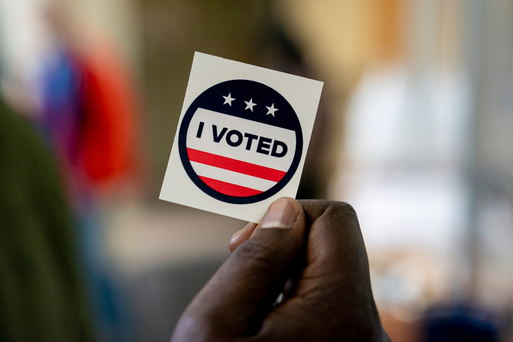 Seorang pemilih memegang stiker Saya Telah Memilih di kantor pusat Pemilu King County di Renton, Washington, Amerika Serikat pada Senin (28/10/2024). / Bloomberg-David Ryder