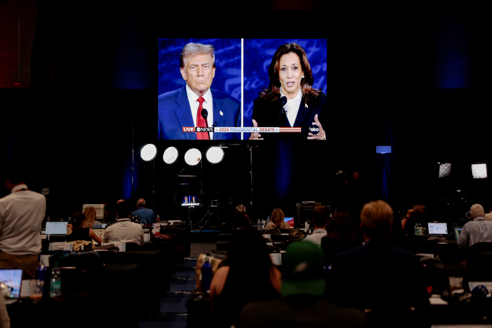 Debat calon presiden AS antara Donald Trump dan Kamala Harris ditayangkan dalam layar di Pennsylvania, Amerika Serikat pada Selasa (10/9/2024). / Bloomberg-Hannah Beier