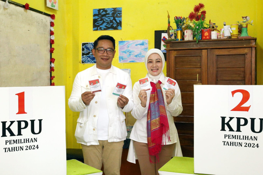 Calon gubernur (Cagub) DKI Jakarta nomor urut 1 Ridwan Kamil (kiri) dan istri Atalia Praratya menggunakan hak pilihnya di Tempat Pemungutan Suara (TPS) 23 Kelurahan Ciumbuleuit, Bandung, Jawa Barat, Rabu (27/11/2024). Bisnis/Rachman