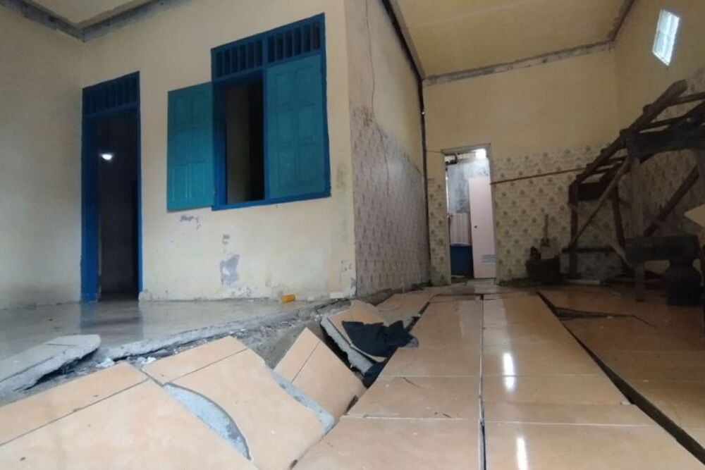 Petugas memeriksa kondisi lantai yang ambles akibat terseret tanah gerak di Pacitan./Antara-BPBD Pacitan.