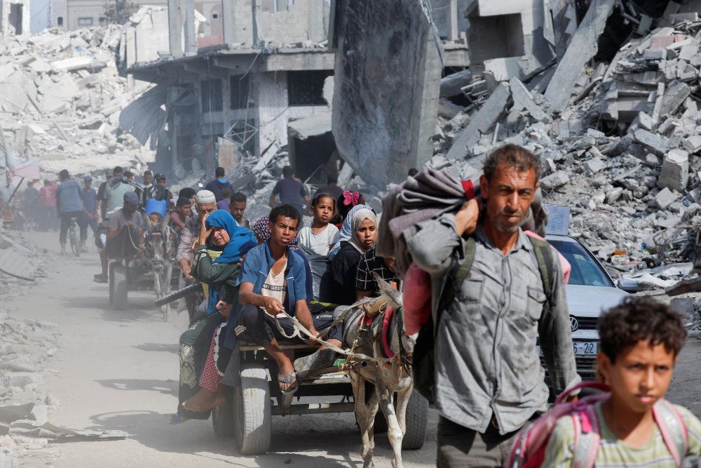 Warga Palestina berjalan untuk kembali ke pemukiman mereka di sisi timur Khan Younis setelah pasukan Israel menarik diri dari daerah tersebut, di Khan Younis, di Jalur Gaza selatan, 30 Juli. REUTERS/Mohammed Salem