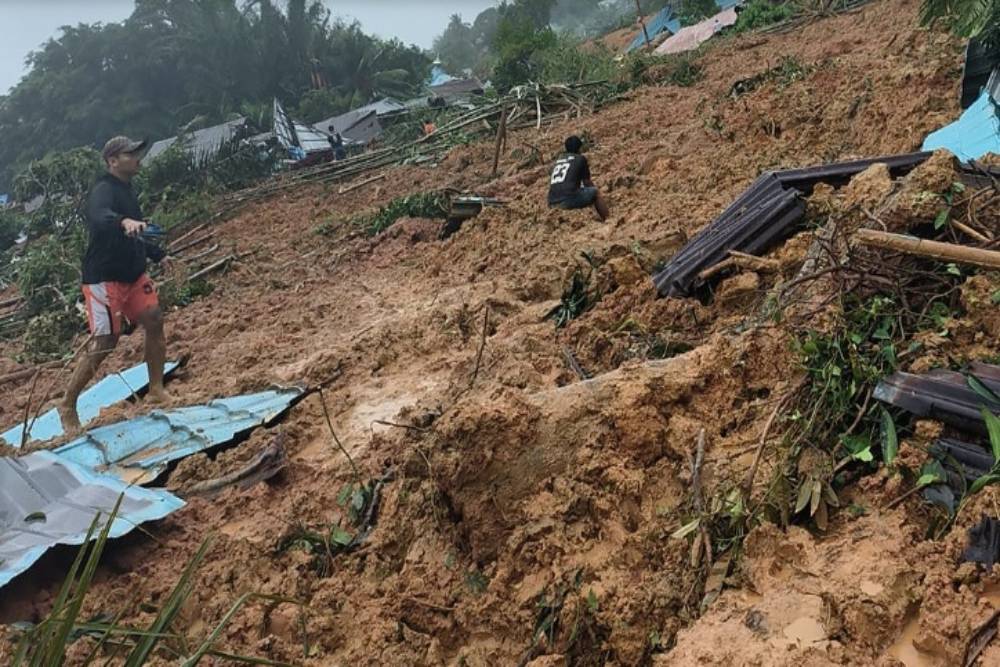 Seorang warga berjalan di lokasi kejadian tanah longsor di Kecamatan Serasan, Kabupaten Natuna, Kepulauan Riau, Senin (6/3/2023)./Dok.BPBD Kabupaten Natuna