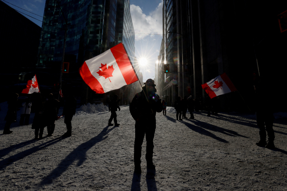Warga memegang bendera Kanada di Ontario, Kanada pada Sabtu (19/2/2022). / Reuters-Blair Gable