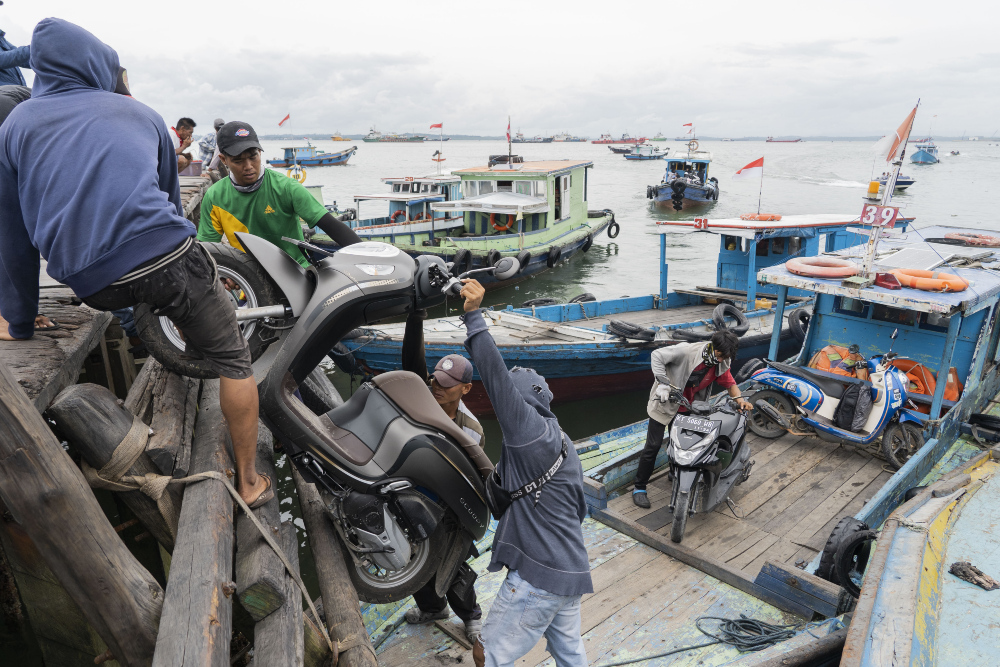 Porter mengangkat sepeda motor dari kapal di Kampung Baru, salah satu wilayah pelabuhan Balikpapan, Kalimantan Timur pada Selasa (7/3/2023). / Bloomberg-Rony Zakaria
