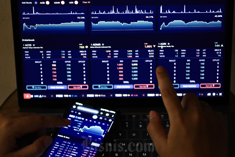 Warga mengakses data saham menggunakan perangkat komputer jinjing dan telepon pintar di Jakarta, Minggu (2/2/2025). Bisnis/Himawan L Nugraha