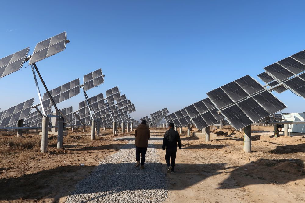 Para pekerja berjalan di salah satu pembangkit listrik tenaga surya di Tongchuan, provinsi Shaanxi, China, 11 Desember 2019./Reuters-Muyu Xu