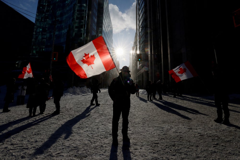 Warga memegang bendera Kanada di Ontario, Kanada pada Sabtu (19/2/2022). / Reuters-Blair Gable