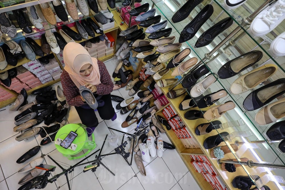 Pedagang memasarkan produk sepatu melalui siaran langsung platform penjualan daring di pasar Tanah Abang, Jakarta, Selasa (12/12/2023). Bisnis/Arief Hermawan P