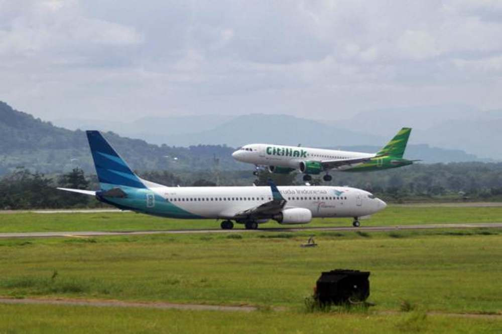 Pesawat Citilink (atas) saat akan mendarat dan pesawat Garuda Indonesia yang akan lepas landas di Bandara Sultan Hasanuddin Makassar, Sulawesi Selatan, Senin (18/2/2019)./Bisnis-Paulus Tandi Bone