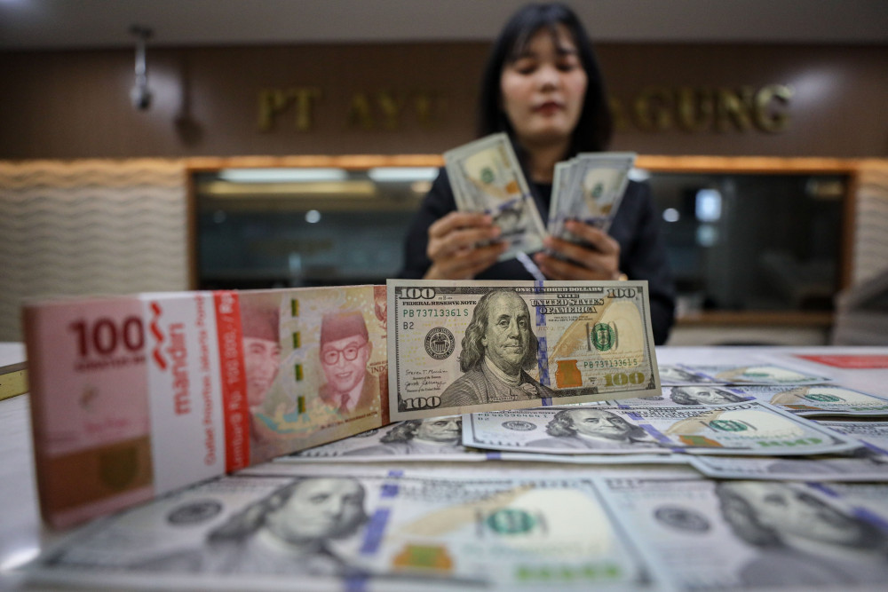 Karyawan menunjukan mata uang rupiah dan dolar AS dan rupiah di salah satu tempat penukaran uang di Jakarta, Senin (12/1/2026). Bisnis/Eusebio Chrysnamurti