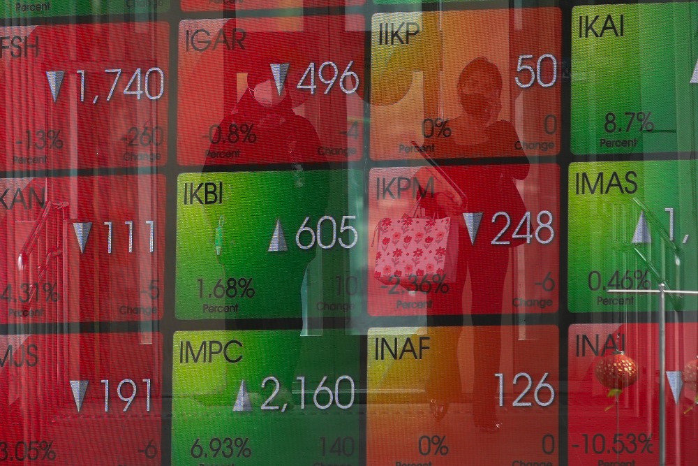 Warga melintas di depan papan informasi saham di Gedung BEI, Jakarta, Jumat (27/2/2026)./Bisnis - Himawan L. Nugraha