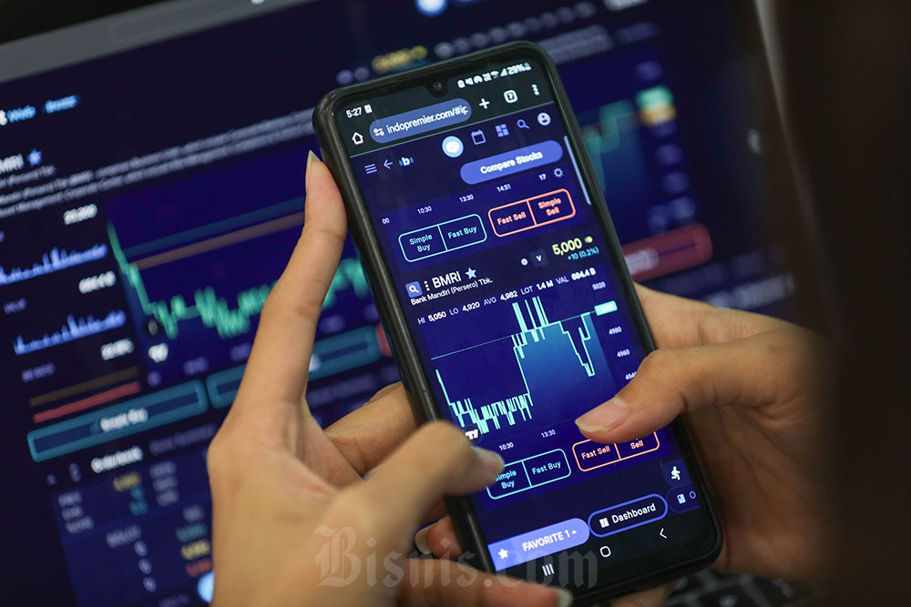 Investor mengamati harga saham dengan gawai di Jakarta, Selasa (16/12). Bisnis/Himawan L. Nugraha