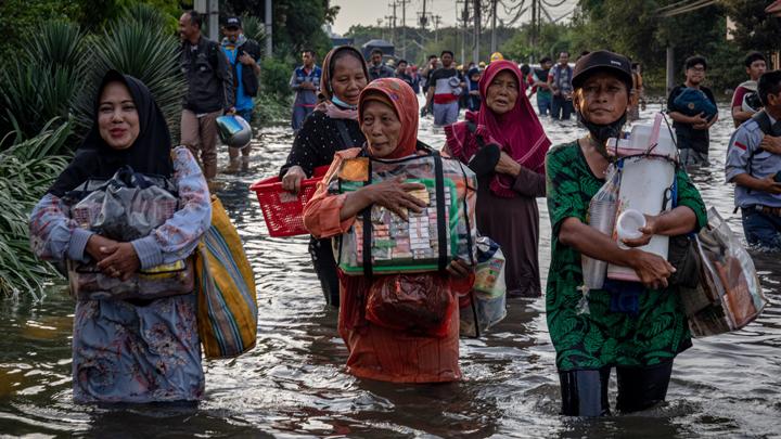 Sejumlah pedagang asongan pelabuhan berjalan menembus banjir limpasan air laut ke daratan atau rob yang merendam kawasan Pelabuhan Tanjung Emas Semarang, Jawa Tengah, Senin, 23 Mei 2022. ANTARA FOTO/Aji Styawan