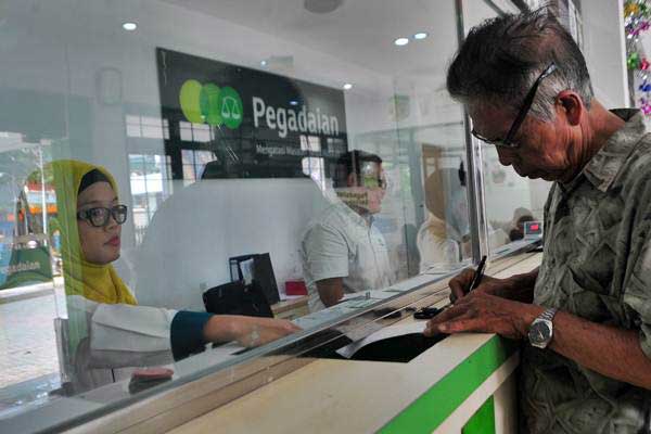 Petugas Pegadaian melayani warga yang menggadaikan barangnya di Kantor Pegadaian Merdeka Palembang, Sumsel, Senin (12/6). - Antara/Feny Selly