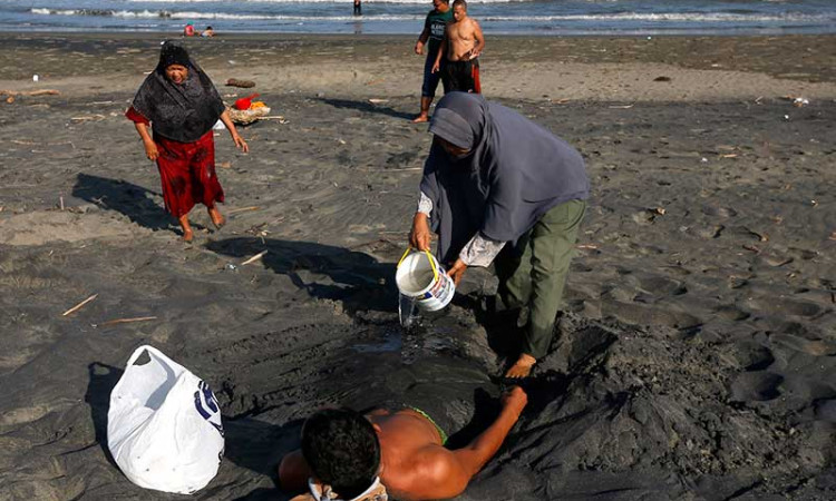 Warga Aceh Melakukan Terapi Pasir Hitam di Pantai Syiah Kuala