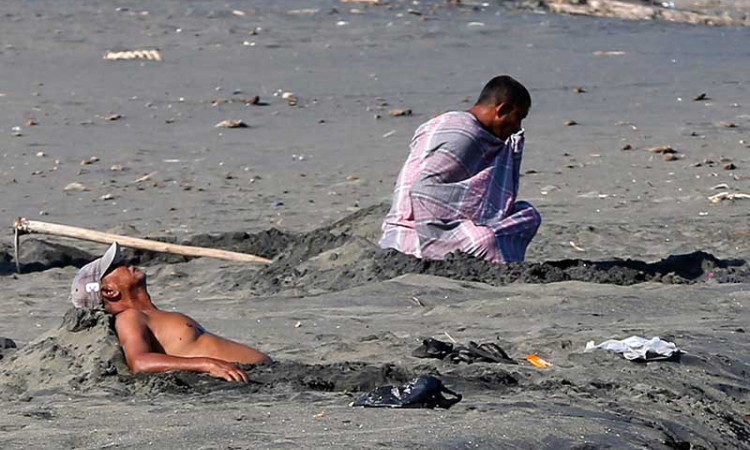 Warga Aceh Melakukan Terapi Pasir Hitam di Pantai Syiah Kuala