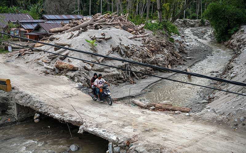 Pengendara sepeda motor melintas di jembatan di atas sungai yang mengalami pendangkalan di Desa Rogo, Sigi, Sulawesi Tengah, Jumat (26/11/2021). Pendangkalan akibat material yang dibawa aliran air sungai itu sangat berpotensi menjadi ancaman terjadinya kembali banjir bandang di desa yang telah beberapa kali diterjang bencana serupa. ANTARA FOTO/Basri Marzuki