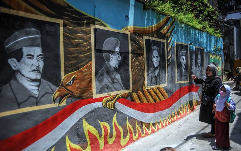 Seorang ibu menunjukkan kepada anaknya Pahlawan Revolusi yang gugur pada peristiwa G30S PKI yang digambar oleh muralis di Cimindi, Cimahi, Jawa Barat, Selasa (27/9/2022). Mural yang digambar oleh muralis dari komunitas Seniman Kreatif Cimindi tersebut bertujuan untuk mengedukasi masyarakat khususnya anak-anak untuk mengenal Pahlawan Revolusi yang gugur pada peristiwa G30S PKI. ANTARA FOTO/Raisan Al Farisi