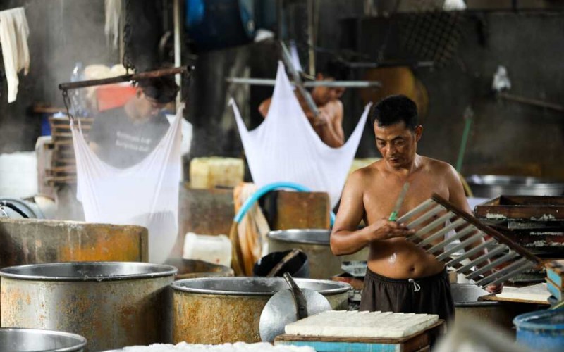 Pekerja beraktivitas di salah satu sentra produksi tahu di Jakarta, Minggu (2/10/2022). Perajin tahu dan tempe berencana menaikkan harga jualnya sebesar 20-30%. Hal tersebut tak terlepas dari reli kenaikan harga kedelai yang menyentuh Rp13.000 per kilogram di tingkat produsen. Bisnis/Suselo Jati