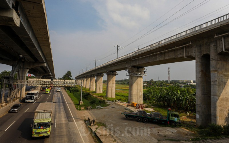 Kendaraan melintas disekitar proyek pembangunan konstruksi Kereta Cepat Jakarta-Bandung, Bekasi, Jawa Barat, Senin (30/1/2023). Progres pembangunan konstruksi Kereta Cepat Jakarta-Bandung telah mencapai sekitar 84 persen. Ditargetkan proyek pembangunan KCJB rampung pada Juni 2023, dan diharapkan dapat beroperasi secara komersial pada Juli 2023. Bisnis/Abdurachma