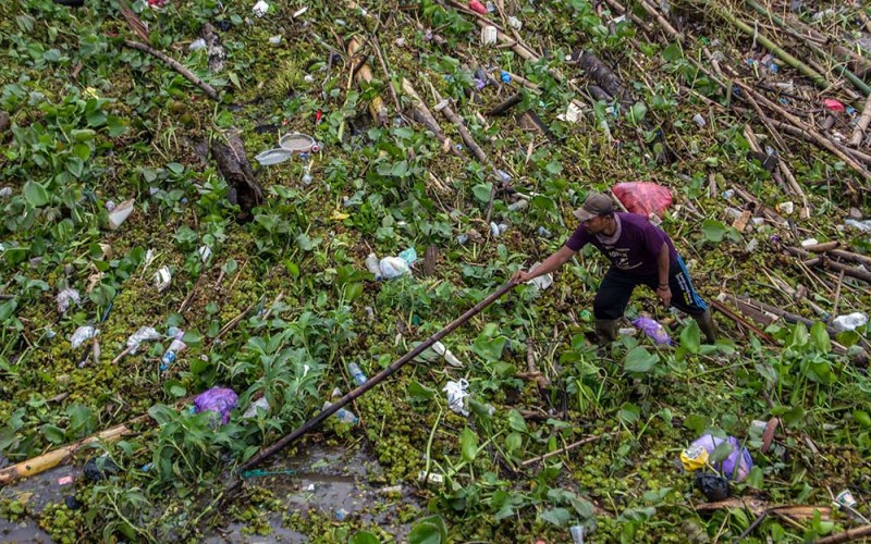 Petugas dari Dinas PUPR Kota Banjarmasin membersihkan tumpukan sampah yang menutupi Sungai Martapura di Banjarmasin, Kalimantan Selatan, Rabu (1/2/2023). Sampah kiriman dalam dua hari terakhir dari hulu sungai akibat intensitas hujan yang tinggi tersebut menyebabkan arus lalu lintas transportasi sungai tersebut terganggu. ANTARA FOTO/Bayu Pratama S