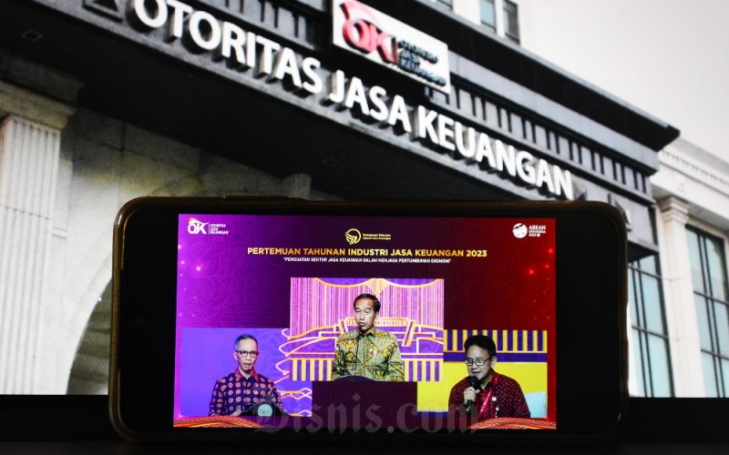 Layar menampilkan Presiden Joko Widodo (tengah), Ketua Dewan Komisioner Otoritas Jasa Keuangan (OJK) Mahendra Siregar (kiri) dan Wakil Ketua Dewan Komisioner OJK Mirza Adityaswara saat memberikan pemaparan dalam acara Pertemuan tahunan industri jasa keuangan (PTIJK) 2023 dengan tema Penguatan sektor jasa keuangan dalam menjaga pertumbuhan ekonomi, Jakarta, Senin (6/2/2023). PTIJK 2023 merupakan puncak acara dari rangkaian agenda OJK bersama industri jasa keuangan pada Desember 2022. Melalui agenda ini, Presiden Jokowi bersama OJK menyampaikan pesan strategis kepada industri dan stakeholder jasa keuangan sebagai upaya untuk menjaga pertumbuhan ekonomi. Bisnis/Suselo Jati