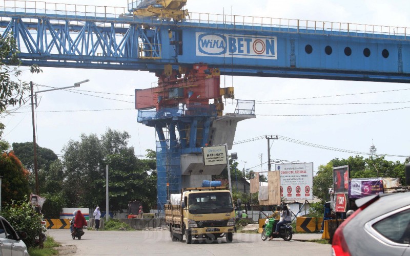 Kendaraan melintas didekat pembangunan jalan layang akses pelabuhan Makassar New Port ke Jalan tol di Makassar, Sulawesi Selatan, Selasa (7/2/2023). PT Wijaya Karya Beton Tbk. (WTON) menargetkan nilai kontrak baru mencapai Rp8,6 triliun pada 2023. Angka ini naik 13,1 persen dari target Rp7,6 triliun pada 2022. Bisnis/Paulus Tandi Bonern