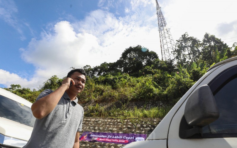Warga menggunakan ponsel dengan latar BTS XL Axiata di Kecamatan Entikong, Kabupaten Sanggau, Kalimantan Barat, Kamis (9/2/2023). Dalam setahun terakhir, jumlah BTS XL Axiata bertambah sebanyak lebih dari 1.100 BTS 4G di seluruh wilayah Kalimantan, angka tersebut meningkat sebesar 42% YoY. Selain itu, infrastruktur jaringan XL Axiata di seluruh Kalimantan diperkuat oleh kabel fiber optic yang jalurnya telah membentang sepanjang lebih dari 9.300 kilometer. Bisnis/Eusebio Chrysnamurti