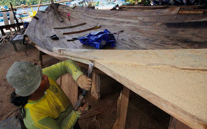 Pekerja menyelesaikan pembuatan kapal nelayan tradisional di Tambakrejo, Sumbermanjing Wetan, Malang, Jawa Timur, Rabu (15/3/2023). Pembuatan kapal nelayan berkapasitas 40 ton yang biasanya dikerjakan selama tiga bulan dengan biaya sekitar RP600 juta itu kini menghabiskan waktu enam bulan dengan biaya Rp800 juta per kapal yang disebabkan sulitnya mendapatkan bahan baku berupa kayu jati berkualitas. ANTARA FOTO/Irfan Sumanjaya