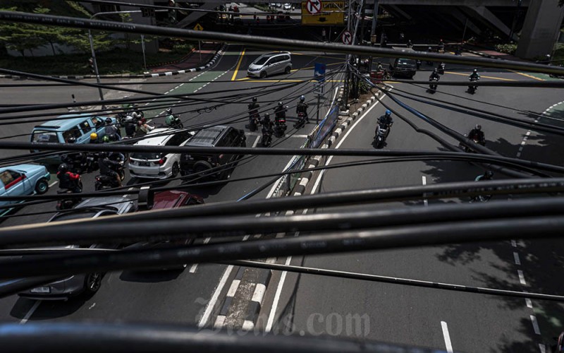 Kendaraan melintas di bawah instalasi kabel utilitas di Jalan Dewi Sartika, Jakarta, Kamis (23/3/2023). Penjabat (Pj) Gubernur DKI Jakarta Heru Budi Hartono memberikan tenggat waktu hingga Juni 2023 kepada seluruh operator jaringan utilitas yang tergabung dalam Asosiasi Penyelenggara Jaringan Telekomunikasi (Apjatel) untuk merapikan kabel semrawut di Jakarta. ANTARA FOTO/Aprillio Akbar