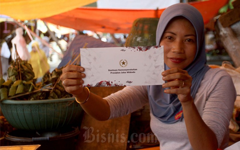 Pedagang memperlihatkan amplop berisi uang tunai dari Presiden Republik Indonesia Joko Widodo di Pasar Terong Makassar, Sulawesi Selatan, Rabu (29/3/2023). Presiden Jowoki melakukan kunjungan kerja ke Sulawesi Selatan meresmikan depo Kereta Api Maros dan Kereta Api Makassar-Parepare serta mengunjungi pasar dan kampung nelayan di Kabupaten Maros dan Makassar. Bisnis/Paulus Tandi Bone