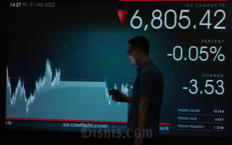 Karyawan melintas di dekat layar pergerakan saham di Bursa Efek Indonesia (BEI), Jakarta, Jumat (31/3/2023). Indeks harga saham gabungan (IHSG) ditutup melemah 0,05 persen atau 3,67 poin menjadi 6.805,27. Sepanjang sesi IHSG bergerak di rentang 6.789,61-6.831,55. Bisnis/Fanny Kusumawardhani