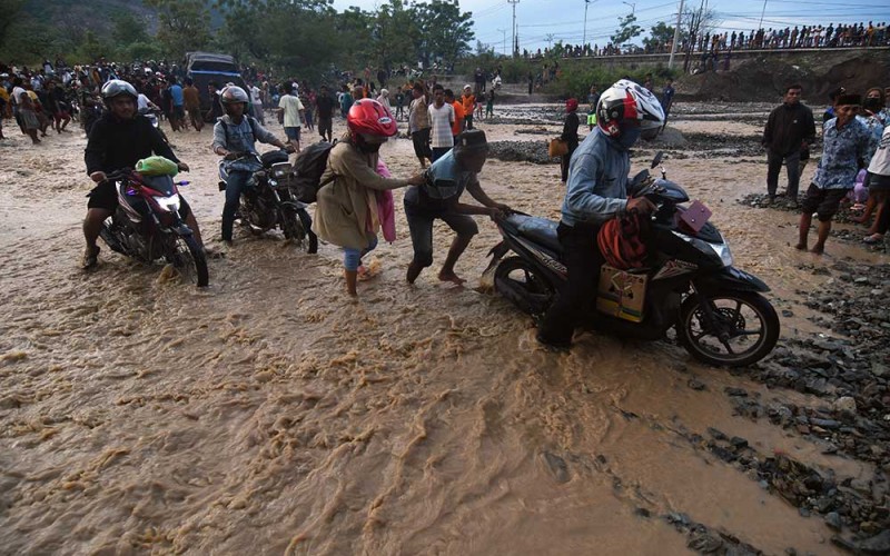 Pengendara melintasi sungai akibat jembatan amblas dan tidak dapat dilalui di Kelurahan Buluri di Palu, Sulawesi Tengah, Jumat (7/4/2023). Jembatan pada jalur penghubung Kota Palu dan Donggala hingga ke Sulawesi Barat dan Sulawesi Selatan serta menjadi salah satu jalur utama bagi pemudik tersebut terputus sehingga pengguna jalan terpaksa melintasi sungai. ANTARA FOTO/Mohamad Hamzah