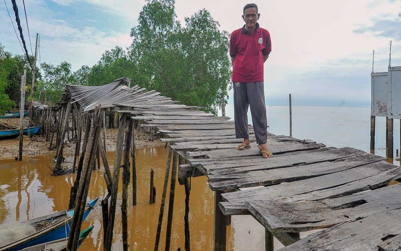 Warga berdiri di ujung jembatan yang rusak di Tanjung Solok, Tanjung Jabung Timur, Jambi, Rabu (24/5/2023). Jembatan yang dibangun dengan konstruksi panggung kayu sepanjang sekitar 300 meter di atas kawasan hutan bakau sejak belasan tahun lalu untuk menghubungkan beberapa RT di pesisir Kuala Jambi itu rusak dan tidak bisa dilewati sejak Selasa (23/5/2023) sehingga menghambat mobilitas warga. ANTARA FOTO/Wahdi Septiawan