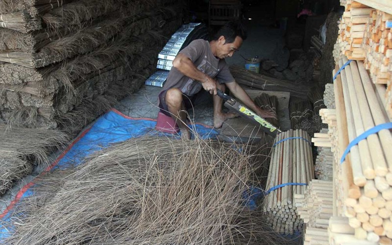Perajin membuat sapu di rumah produksi peralatan kebersihan Dua Putri di Dumplengan, Ngawi, Jawa Timur, Senin (29/5/2023).  Produksi kerajinan sapu sebanyak 6.000 buah per minggu dengan memberdayakan warga sekitar tersebut dijual ke berbagai kota di Indonesia dengan harga Rp6.500 hingga Rp13 ribu per buah. ANTARA FOTO/Ari Bowo Sucipto