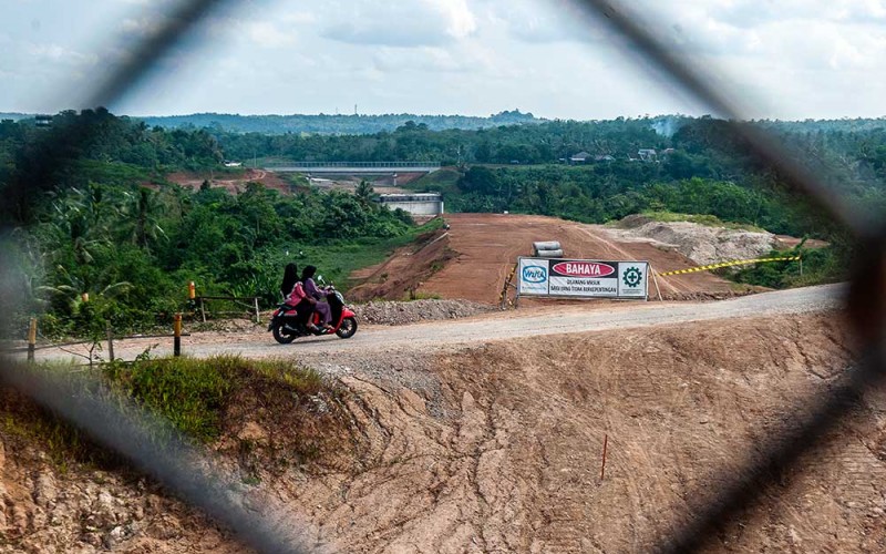 Warga melintas di sekitar jalur pembangunan jalan tol Rangkasbitung-Panimbang di Lebak, Banten, Senin (5/6/2023). Pemerintah menyiapkan anggaran belanja untuk infrastruktur ruas jalan nasional baik tol maupun non tol pada tahun 2023 sebesar Rp203 triliun dan terdistribusi di tiap-tiap pulau di Indonesia. ANTARA FOTO/Muhammad Bagus Khoirunas