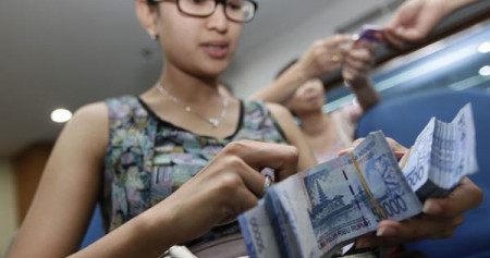 Seorang perempuan tengah menghitung duit/Bloomberg