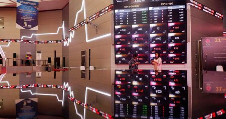 Karyawati berkomunikasi di dekat monitor pergerakan Indeks Harga Saham Gabungan (IHSG) di Bursa Efek Indonesia, Jakarta, Selasa (3/7/2018)./JIBI-Nurul Hidayat