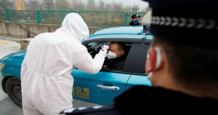 Seorang pekerja medis dalam pakaian pelindung memeriksa suhu tubuh seorang pengemudi di sebuah pos pemeriksaan di luar Kota Yueyang, Provinsi Hunan, dekat perbatasan dengan Provinsi Hubei yang dikunci setelah pecahnya virus corona baru, China, 28 Januari 2020./Reuters