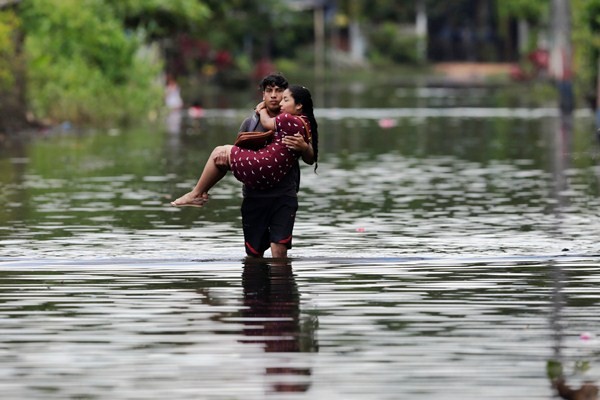 Seorang pria menggendong istrinya menembus genangan air./Reuters-Henry Romero
