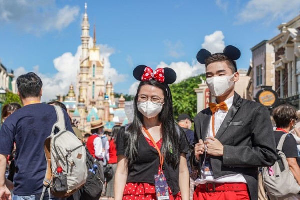 Pelancong berfoto mengunakan masker di Disneyland Hong Kong/ Bloomberg