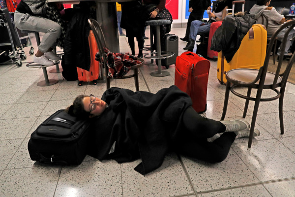 Seorang penumpang berbaring untuk beristirahat di Terminal Selatan di Bandara Gatwick, London, setelah drone yang terbang ilegal di sekitar bandara memaksa pihak bandara menunda penerbangan dari dan ke bandara tersebut, Kamis (20/12/2018)./Reuters-Peter Nicholls