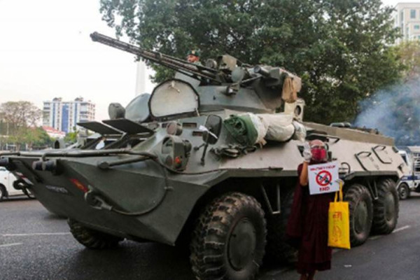 Seorang biksu Buddha memegang tanda berdiri di samping kendaraan lapis baja saat protes terhadap kudeta militer, di Yangon, Myanmar, Minggu (14/2/2021)./Antara/Reuters-Stringer