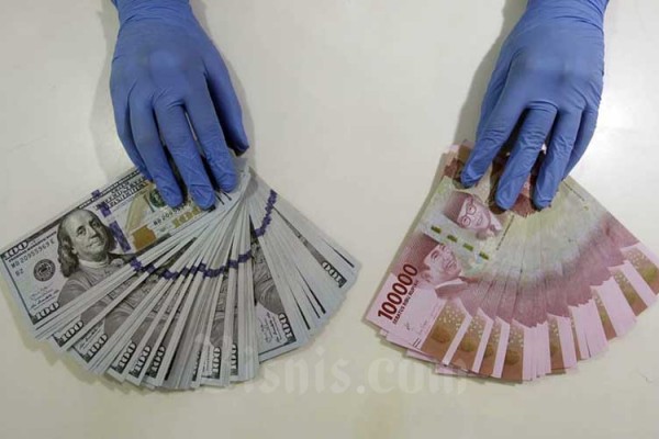 Karyawan merapikan uang dolar dan rupiah di Kantor Cabang Bank Mandiri di Jakarta, Kamis (14/1/2021). Bisnis/Himawan L Nugraha
