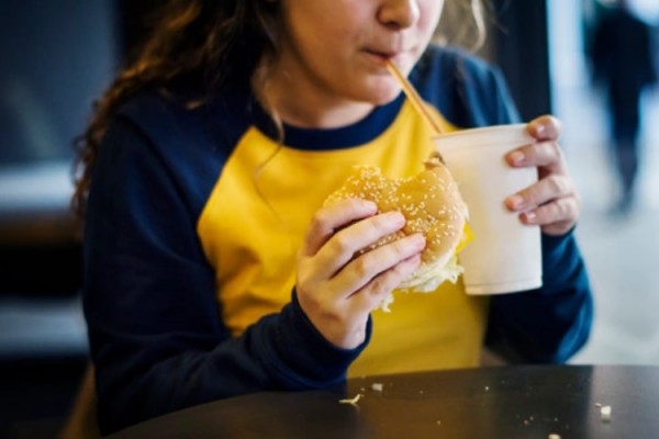 Ilustrasi anak mengonsumsi fast food yang bisa menimbulkan obesitas/Freepik